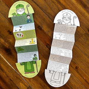 Puede incluir: Dos manualidades de papel con el tema del Día de San Patricio. Cada una presenta una ilustración de dibujos animados de San Patricio, junto con texto que describe su vida y el significado del trébol. La parte inferior de cada manualidad dice "PRAY FOR US!"