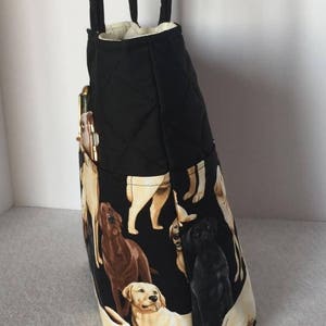 May include: Black quilted tote bag with a zippered pocket and a print of Labrador Retrievers in various colors. The bag has two black straps.