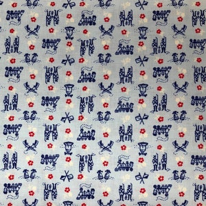 May include: A blue and white fabric with a repeating pattern of small red flowers, musical notes, and a marching band. The fabric has a light blue background.