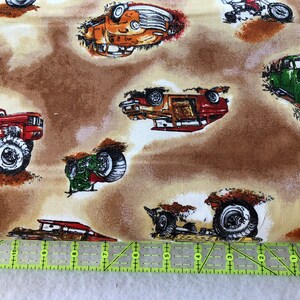 Puede incluir: Una tela marr&oacute;n con un patr&oacute;n repetido de varios camiones y coches. Los camiones y los coches son de diferentes colores, incluyendo rojo, verde, naranja y azul. La tela tiene un aspecto y una sensaci&oacute;n vintage.