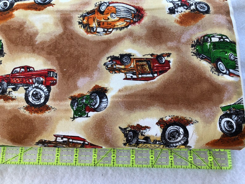 Puede incluir: Una tela marr&oacute;n con un patr&oacute;n repetido de varios camiones y coches. Los camiones y los coches son de diferentes colores, incluyendo rojo, verde, naranja y azul. La tela tiene un aspecto y una sensaci&oacute;n vintage.