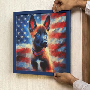 May include: A framed painting of a brown and black puppy with a red collar, sitting in front of an American flag. The frame is a dark blue color.
