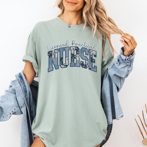 May include: A light green t-shirt with the words "Licensed Practical Nurse" in a blue patchwork design. The shirt has short sleeves and a relaxed fit.