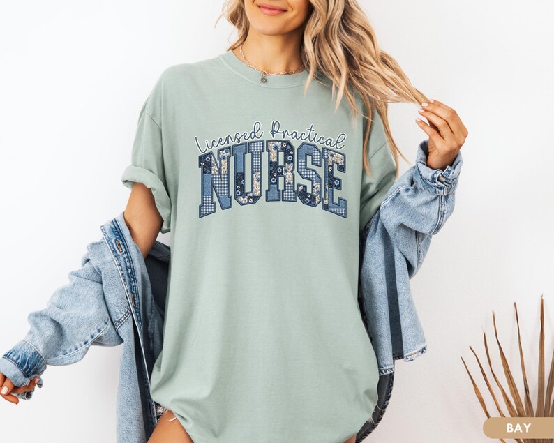 May include: A light green t-shirt with the words "Licensed Practical Nurse" in a blue patchwork design. The shirt has short sleeves and a relaxed fit.