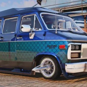 May include: A custom blue and teal van with a white front bumper and chrome accents. The van features a unique design with a patterned teal section and a dark blue roof. The wheels have a classic, vintage style.