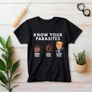 May include: Black t-shirt with the text "KNOW YOUR PARASITES" and illustrations of a deer tick, dog tick, and a cartoon of Donald Trump labeled "LUNA TICK".