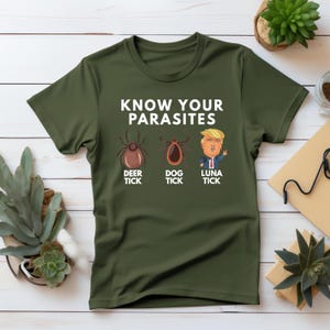 May include: A green t-shirt with the text "KNOW YOUR PARASITES" and three illustrations. The illustrations are of a deer tick, a dog tick, and a cartoon of Donald Trump labeled "LUNA TICK".