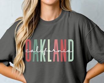 Maglietta tinta in capo Oakland California, caratteri alla moda, tonalità natalizie, maglietta Oakland