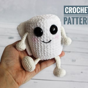 May include: A handmade white crochet character with large black eyes, rosy cheeks, and a smiling mouth. The character has small arms and legs. The text "CROCHET PATTERN" is in a blue box in the upper right corner.