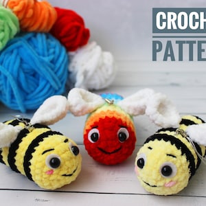Puede incluir: Tres juguetes de abeja de crochet con alas blancas. Una abeja es amarilla y negra, otra es roja y arcoíris, y otra es amarilla y negra con mejillas rosadas. El texto "CROCHET PATTERN" está en el fondo.