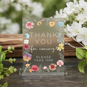 May include: Clear acrylic sign with floral border and the text "THANK YOU for coming! PLEASE TAKE ONE." The sign features a variety of colorful watercolor flowers, including pink, yellow, and blue blooms, with green foliage.