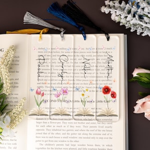 May include: A clear acrylic bookmark featuring floral and butterfly designs. The bookmark has four sections with tassels in yellow, silver, blue, and black. Text on the bookmark reads "Second Story A Little Boy and a Little Girl."