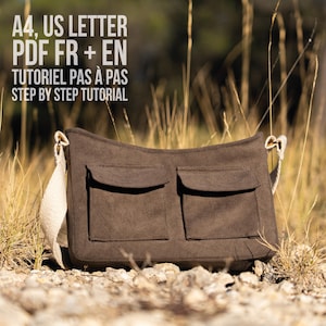 Op de afbeelding: Een bruine stoffen schoudertas met twee voorzakken en een brede beige riem. De tekst luidt: A4, US LETTER, PDF FR + EN, TUTORIEL PAS À PAS, STEP BY STEP TUTORIAL. De tas heeft een rechthoekige vorm met afgeronde hoeken.