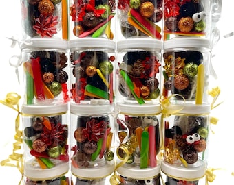 May include: A stack of clear jars filled with decorative elements. Each jar contains glittery balls, colorful sticks, and other embellishments. The jars are tied with ribbons, creating a festive display.