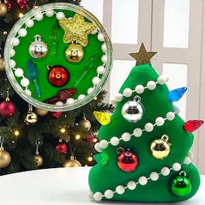 May include: A green Christmas tree decoration with white bead garland and colorful lights. The tree is adorned with silver, gold, and red ornaments. A clear container holds additional ornaments and a gold star.