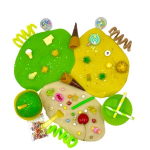 May include: A variety of green, yellow, and beige play dough with sprinkles, candy, and other decorations. The play dough is arranged in a circle with a green cupcake in the center.