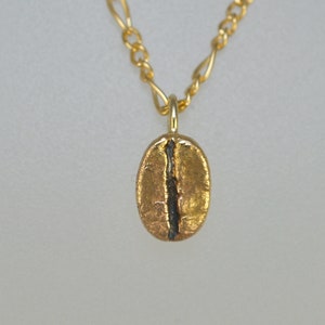 May include: A gold chain necklace with a gold coffee bean pendant.