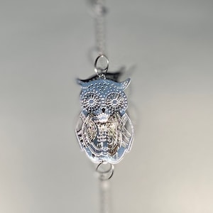 May include: A silver owl charm hangs from a silver chain with a clear iridescent crystal teardrop pendant.