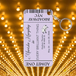 May include: A light purple keychain shaped like a theater ticket. The ticket reads "Mariska Hargitay in EVERY BRILLIANT THING" with the Hudson Theatre address and dates. A silver chain and ring are attached.