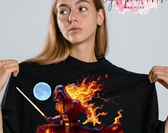 Op de afbeelding: Een zwart T-shirt met een afbeelding van Darth Vader die in vlammen staat, een lightsaber vasthoudt en springt voor een blauwe maan.