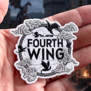 May include: Embroidered patch with the text "FOURTH WING" in bold black letters, surrounded by a gray floral design and black dragon silhouettes. The phrase "FLY...OR DIE" is above the main text. The patch has a white background.