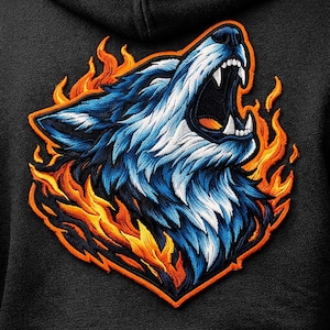 May include: Embroidered patch showing a snarling wolf's head in blue and white, encircled by orange and yellow flames. The patch is outlined in orange, set against a black background, possibly a hoodie or jacket.