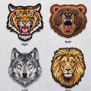 May include: Embroidered patches featuring animal faces: a roaring tiger, a snarling bear, a wolf, and a lion. Each patch has detailed stitching and vibrant colors. The text "tiger", "bear", "wolf", and "lion" is below each patch.