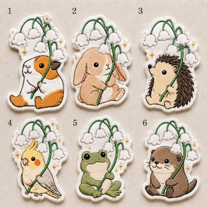 May include: Six embroidered patches featuring cute animals holding lily of the valley flowers. The animals include a guinea pig, a rabbit, a hedgehog, a cockatiel, a frog, and an otter. Each patch has small yellow star accents and white borders.