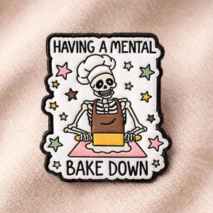 May include: A white patch with a black border featuring a skeleton chef wearing a chef's hat and apron, rolling dough. The text "HAVING A MENTAL BAKE DOWN" is at the top and bottom, with star accents.