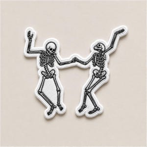 May include: Two embroidered patches featuring dancing skeletons in black and white. The skeletons are holding hands and have their arms raised in a celebratory pose. The patches have a white border and are set against a neutral background.