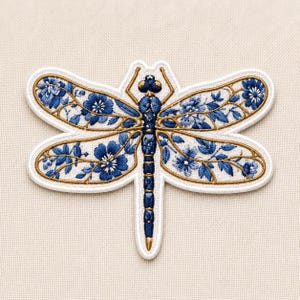 May include: An embroidered dragonfly patch featuring a white background with intricate blue floral patterns on the wings. The body is detailed with dark blue and gold thread, and the entire design is outlined with a thick white border.