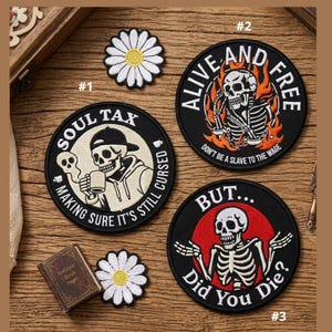 May include: A collection of embroidered patches with skull designs and the phrases "Soul Tax", "Alive and Free", and "But... Did You Die?". The patches are black with white and orange accents. Two daisy patches are also included.