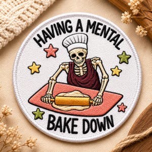 May include: A round, white patch with the text "HAVING A MENTAL BAKE DOWN" encircling a skeleton chef rolling dough. The skeleton wears a chef's hat and apron, with star accents in pink, yellow, and green.
