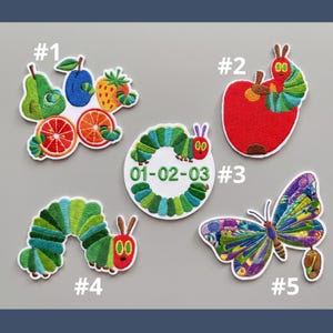 May include: Embroidered patches with vibrant designs. Includes a fruit medley, a red apple with a caterpillar, a green caterpillar with the date 01-02-03, a curved green caterpillar, and a butterfly with colourful wings. Each patch has a white border.