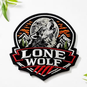May include: A circular embroidered patch featuring a gray wolf howling at a full moon against a black background. The design includes white mountains, orange clouds, and green trees. The text LONE WOLF is in white with three red claw marks below.