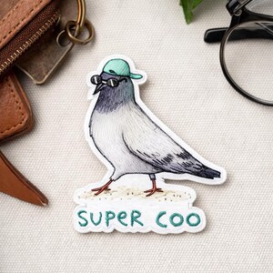May include: Embroidered patch featuring a pigeon wearing sunglasses and a green cap. The bird is in shades of gray, white, and black, with red feet. The patch has the words "SUPER COO" in green lettering.