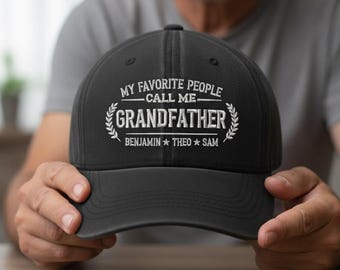 May include: Black baseball cap with the text "MY FAVORITE PEOPLE CALL ME GRANDFATHER" in white. The names Benjamin, Theo, and Sam are below the word Grandfather. The cap is being held by a person.