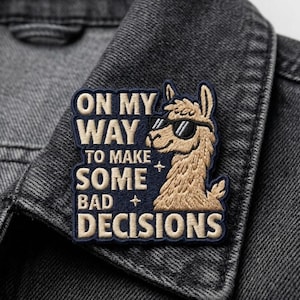 May include: Embroidered patch featuring a llama wearing sunglasses and the text "ON MY WAY TO MAKE SOME BAD DECISIONS" in white and gold. The patch is on a dark grey denim jacket.