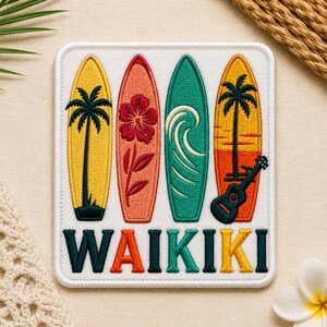 May include: Embroidered patch featuring four surfboards in yellow, coral, teal, and orange, each with unique designs like a palm tree, hibiscus flower, and wave. The word "WAIKIKI" is embroidered in green, orange, and yellow below the surfboards. A black ukulele is on the right.