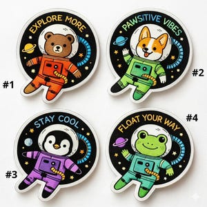 May include: Four embroidered patches featuring cartoon animals in astronaut suits. The patches include a bear, a corgi, a penguin, and a frog, each with a unique phrase: "Explore More," "Pawsitive Vibes," "Stay Cool," and "Float Your Way."
