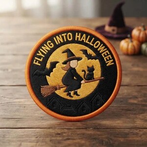 May include: A circular embroidered patch featuring a yellow full moon against a black background. The design shows a witch on a broomstick with a black cat and bats. The text FLYING INTO HALLOWEEN is stitched in yellow along the top border.