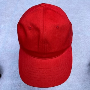 May include: A solid red baseball cap with a curved brim. The cap has a six-panel design with a button on top and eyelets for ventilation. The hat is made of a smooth, durable fabric.