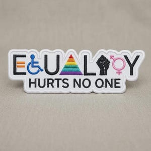 May include: Embroidered patch with the word "EQUALITY" in black, blue, rainbow, pink, and white. The patch includes symbols for disability, LGBTQ+, and a raised fist. The text "HURTS NO ONE" is below the word "EQUALITY".