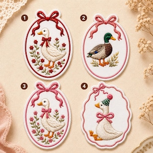 May include: Embroidered patches featuring duck designs. Each patch has a white background with a duck in the center, surrounded by floral and ribbon details. The ducks are in various poses, with different colored bows and hats.