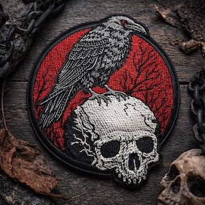 May include: Embroidered patch featuring a detailed black raven with red eyes perched atop a skull. The raven and skull are set against a red circular background with a black border. The patch has a gothic or dark aesthetic.