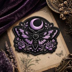 May include: Embroidered patch featuring a moth with purple wings and a crescent moon. The moth is set against a black background with floral accents, including roses. The patch is on a vintage paper background.