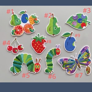 May include: A collection of colorful embroidered patches featuring fruits, leaves, a caterpillar, and a butterfly. The patches include a pear, orange slices, cherries, a strawberry, and a blue plum. The caterpillar and butterfly have vibrant colors.