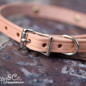 May include: A light pink leather dog collar with a silver buckle and a silver D-ring.