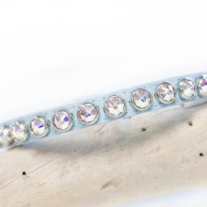May include: A light blue leather pet collar with clear iridescent rhinestones.