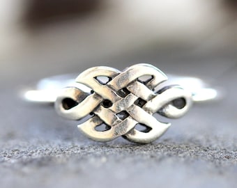 May include: A silver ring with a Celtic knot design. The knot is intricate and detailed, and the ring is polished to a shine.